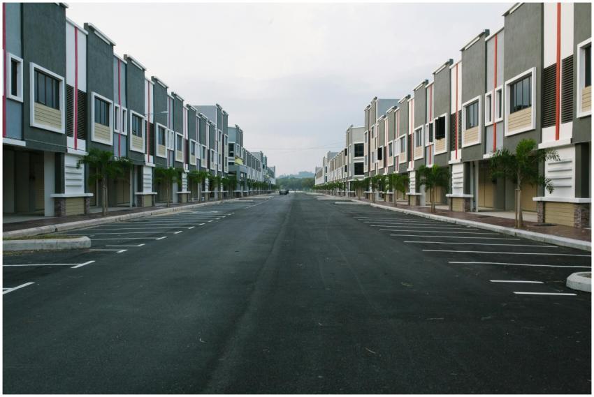 A quiet, empty urban street flanked by modern cond