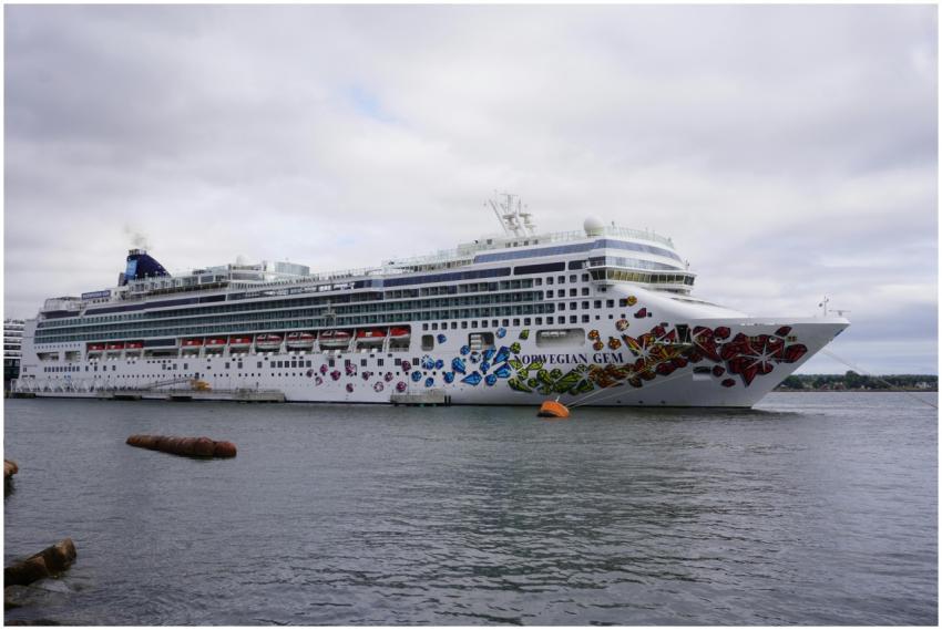 The Norwegian Gem cruise ship docked at a port wit