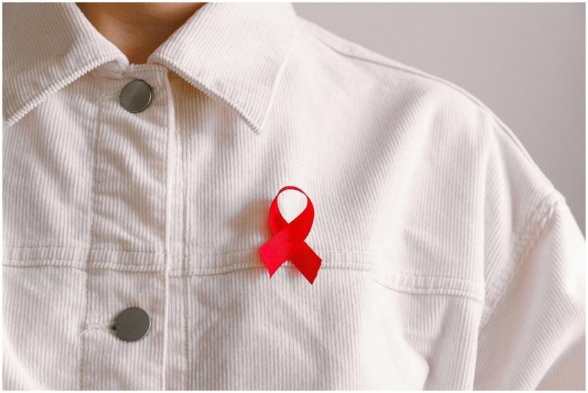Red ribbon for HIV/AIDS awareness pinned on a whit