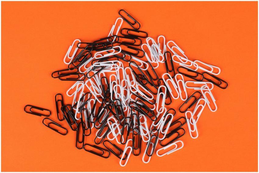A pile of monochrome paper clips on a vibrant oran
