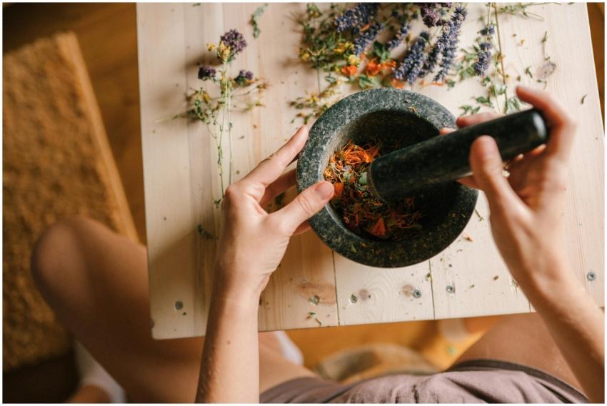 A person grinding colorful dried herbs and flowers