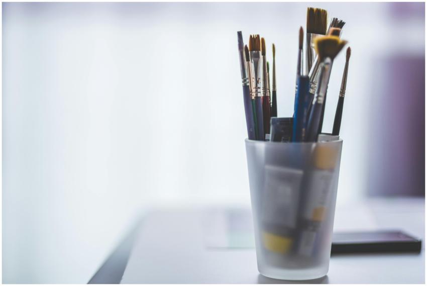 An assortment of paint brushes in a translucent cu