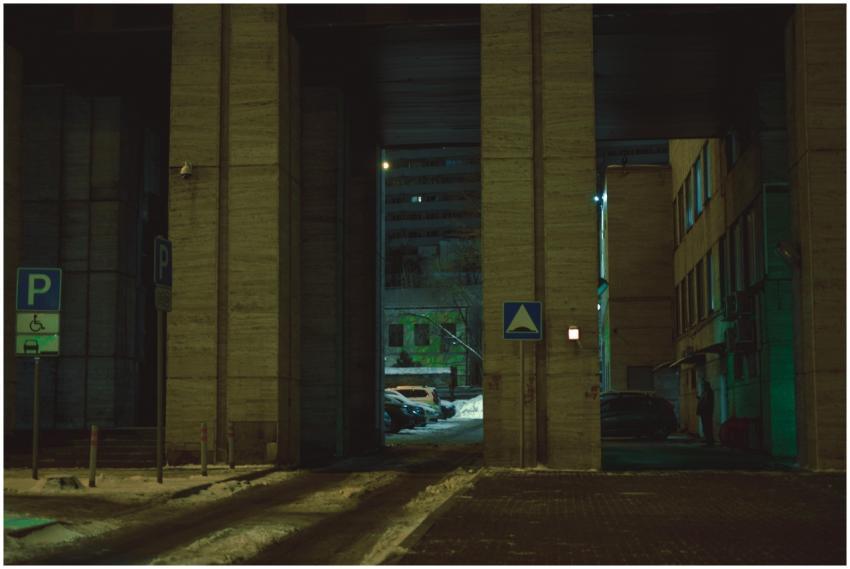 Dimly lit urban street with parking signs and buil