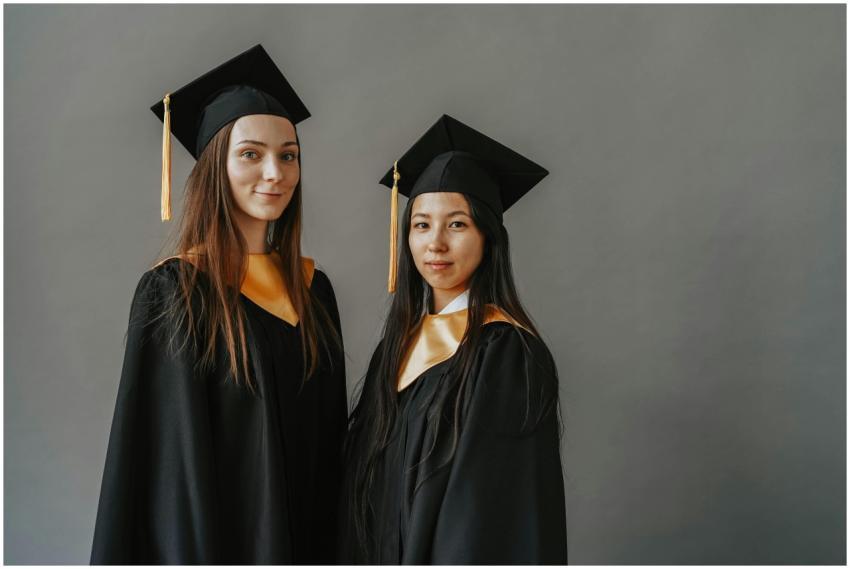 Two graduates posing in traditional gowns and caps