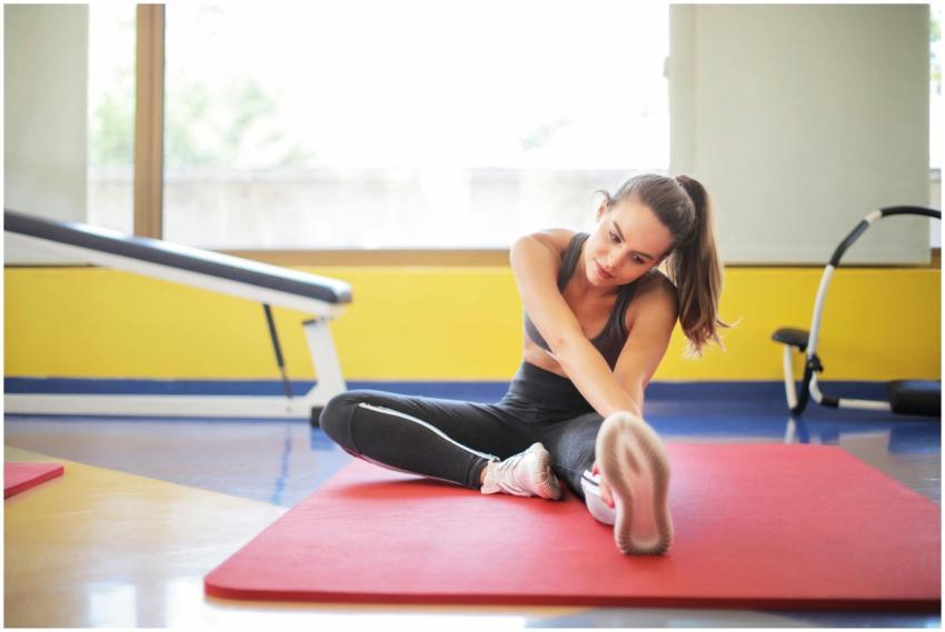 Female athlete stretching on a red yoga mat indoor