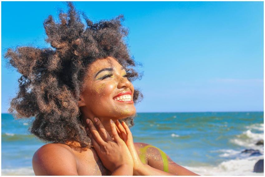 A joyful woman with afro hair smiling brightly on