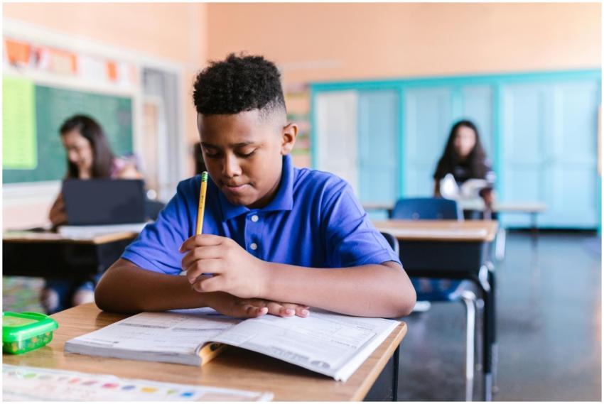 African American boy in a classroom, reading and h