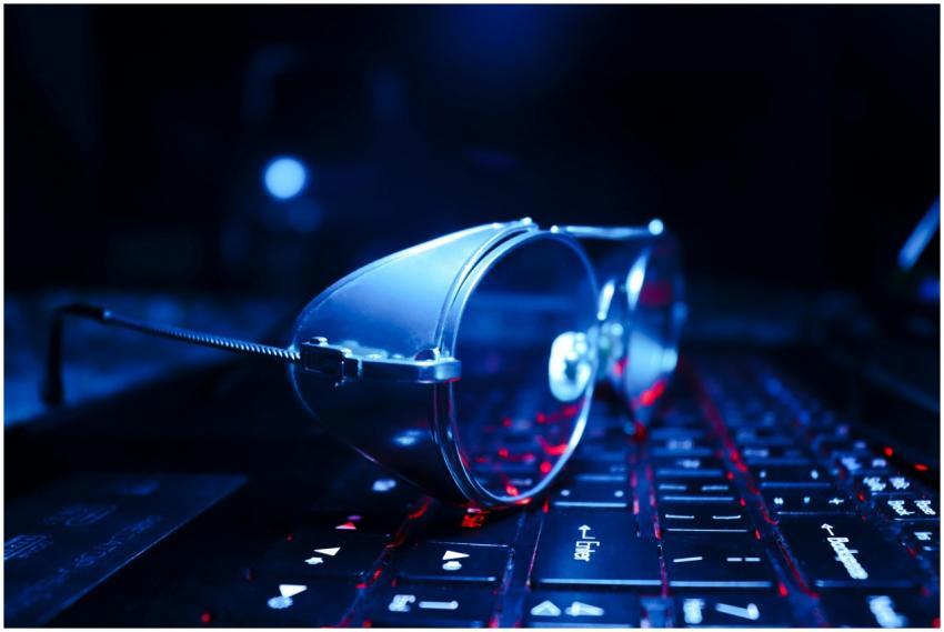 Close-up of eyeglasses on a glowing laptop keyboar