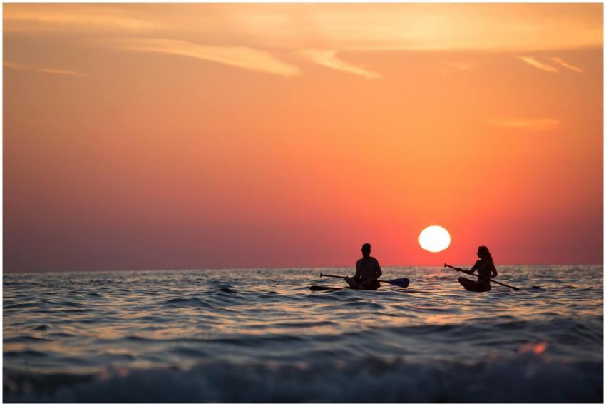 Silhouette of a couple paddleboarding on the ocean