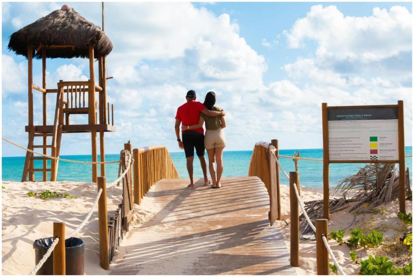 A couple walks hand in hand on a footbridge toward