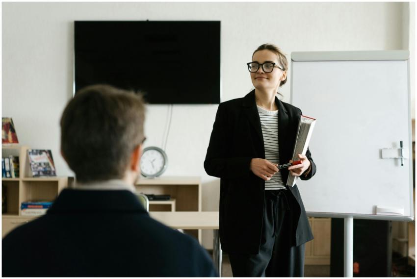 Caucasian female teacher in black blazer holding b