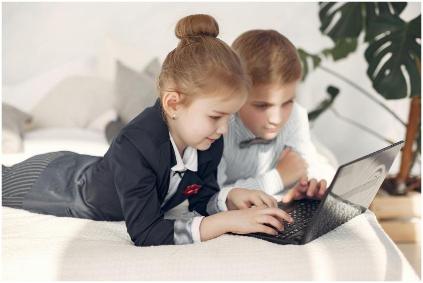 Two children dressed in formal attire using a lapt