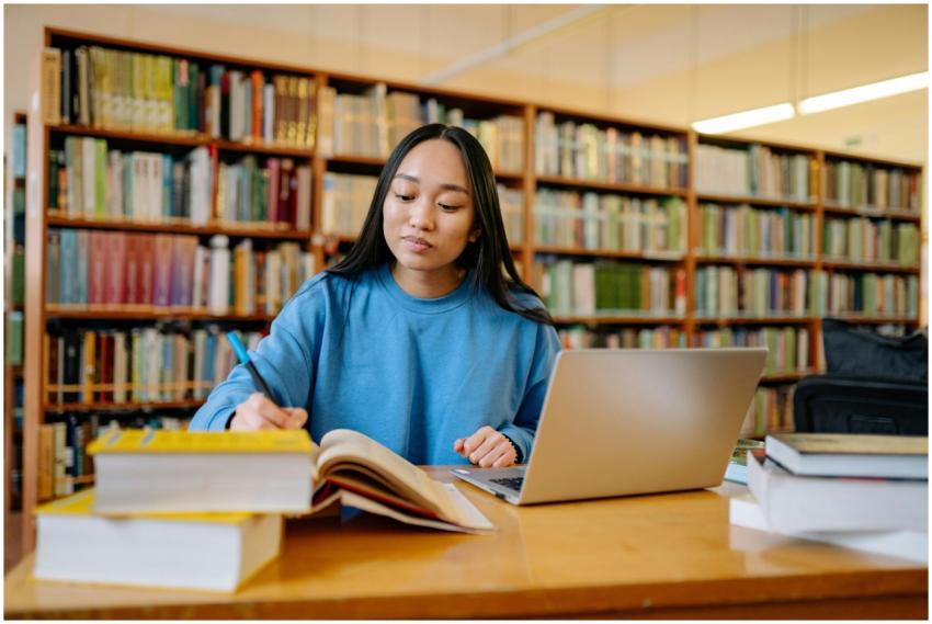 Young woman studying in a library with books and l
