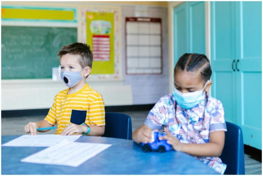 Two children wearing masks learn and play in a bri