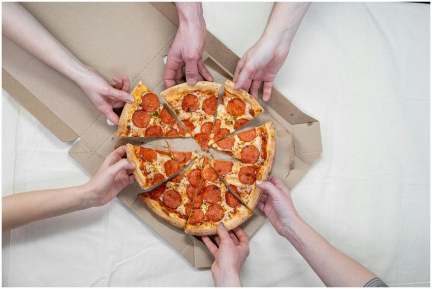 Multiple hands reaching for pepperoni pizza on a t
