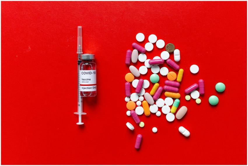 COVID-19 vaccine vial and colorful pills on a vibr
