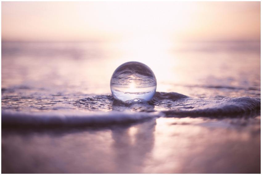 A glass sphere reflecting the sunset on ocean wave