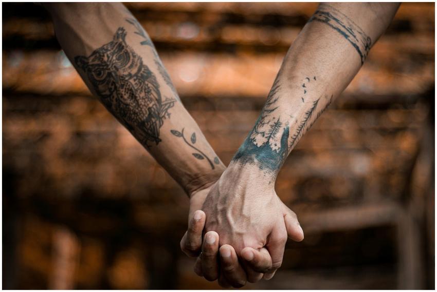 Close-up of tattooed hands holding each other, sym