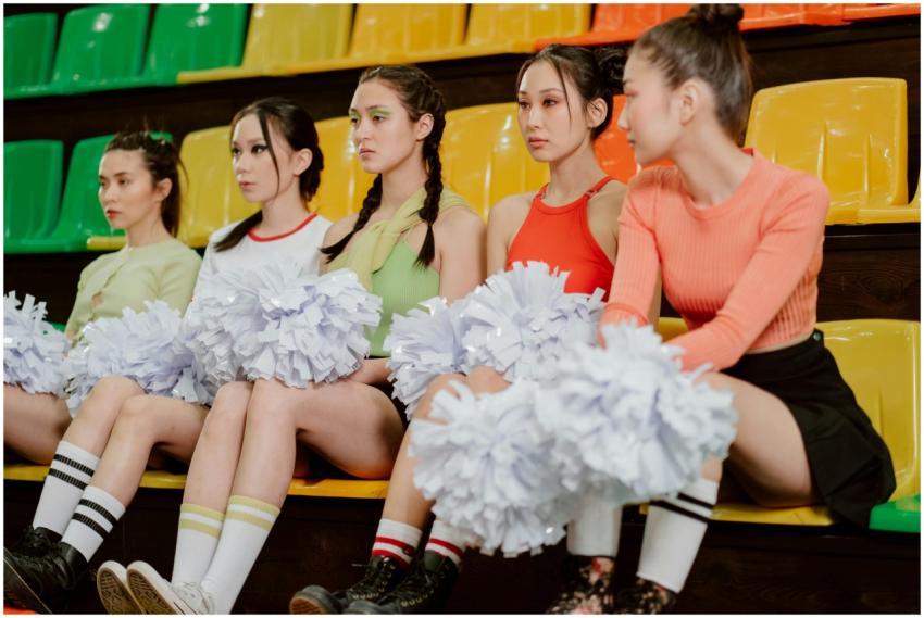 Group of young cheerleaders seated with pom poms i