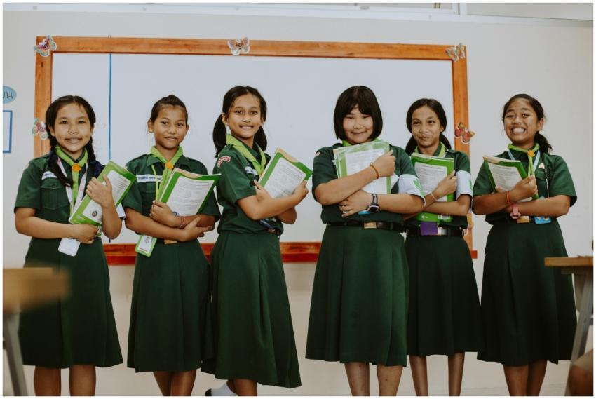 Six Asian Girl Scouts in uniform smiling and holdi