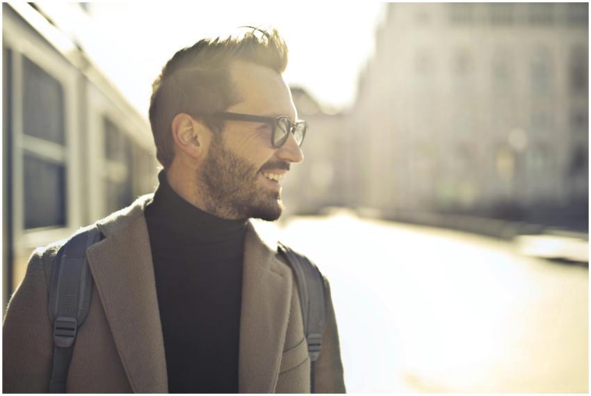 Smiling man with glasses and coat enjoying a sunny