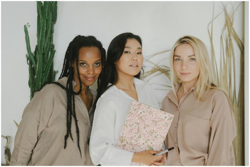 Three diverse women standing together with a noteb