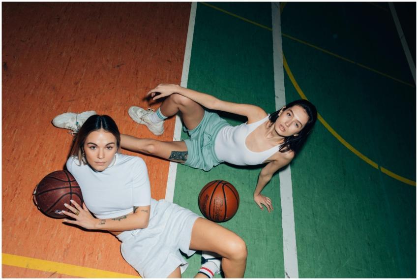 Two women relaxing on a colorful basketball court