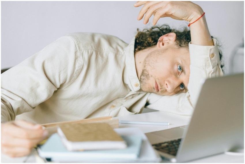 A tired Caucasian man at a desk, showing signs of