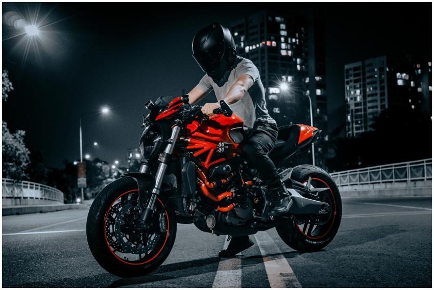 A biker on a red Ducati motorcycle rides through a