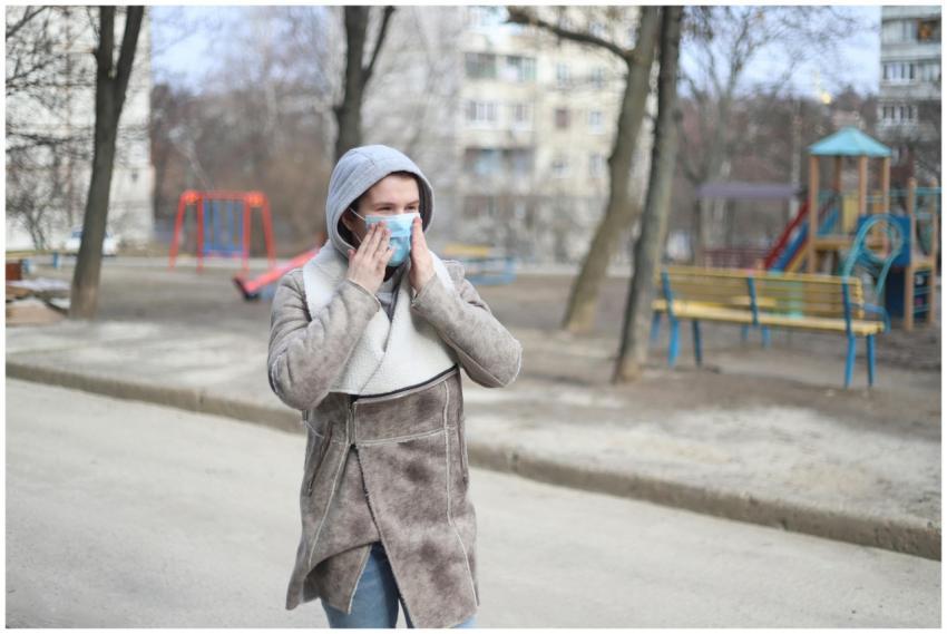 Woman wearing a mask in a chilly urban park, highl