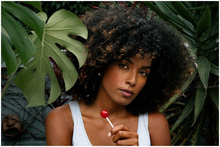 A woman with afro-textured hair holds a lollipop o