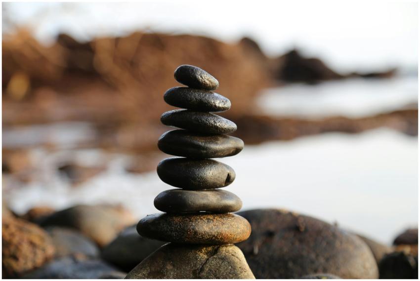 A stack of smooth stones artfully balanced by a wa