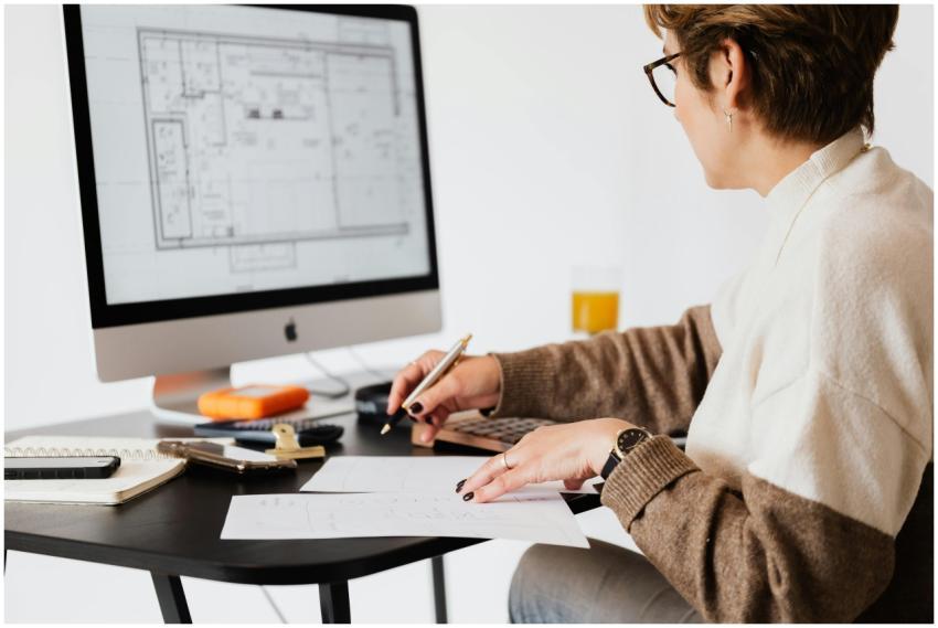 Woman designing architectural blueprints using des