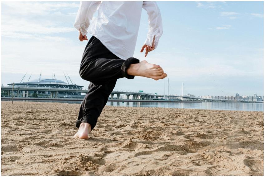 A person runs barefoot on a sandy beach with a cit