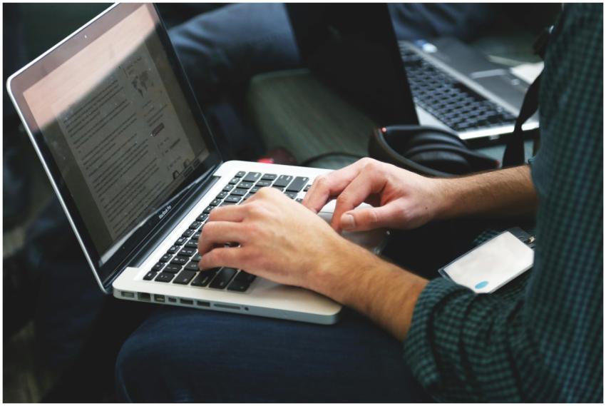 A programmer typing on a laptop in an indoor setti