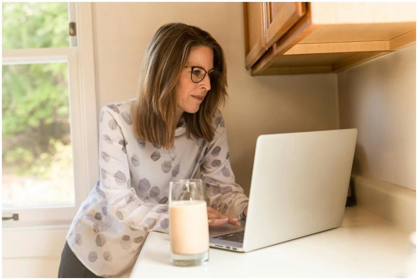 A woman working on a laptop in a home kitchen, ill