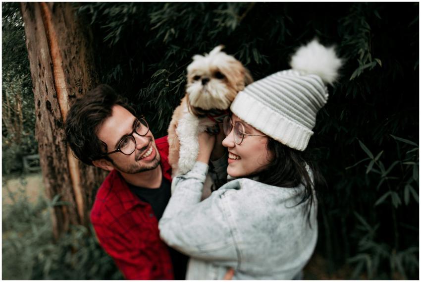 A joyful couple smiling and holding a Shih Tzu dog