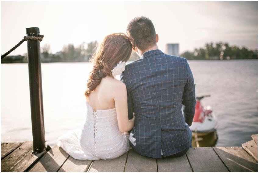 Bride and groom sitting on a dock by a serene lake