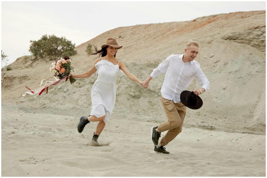 A joyful young couple running hand in hand on a sa
