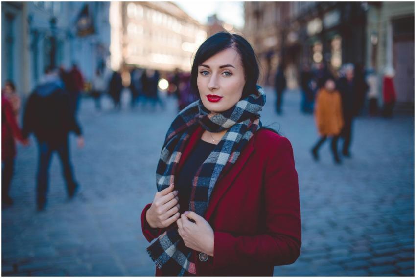 Young woman in red coat and plaid scarf standing i