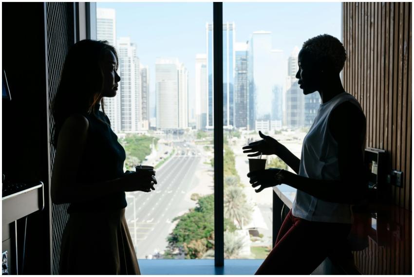 Two businesswomen engage in discussion by a large
