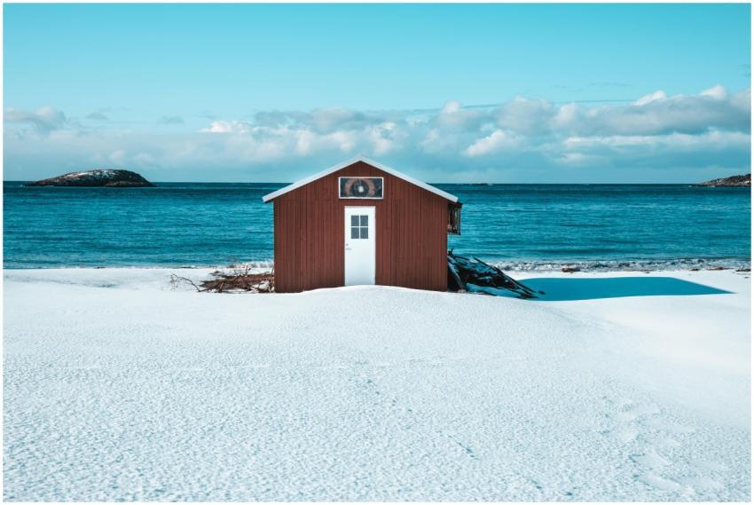 A solitary red hut on a snowy beach with the blue