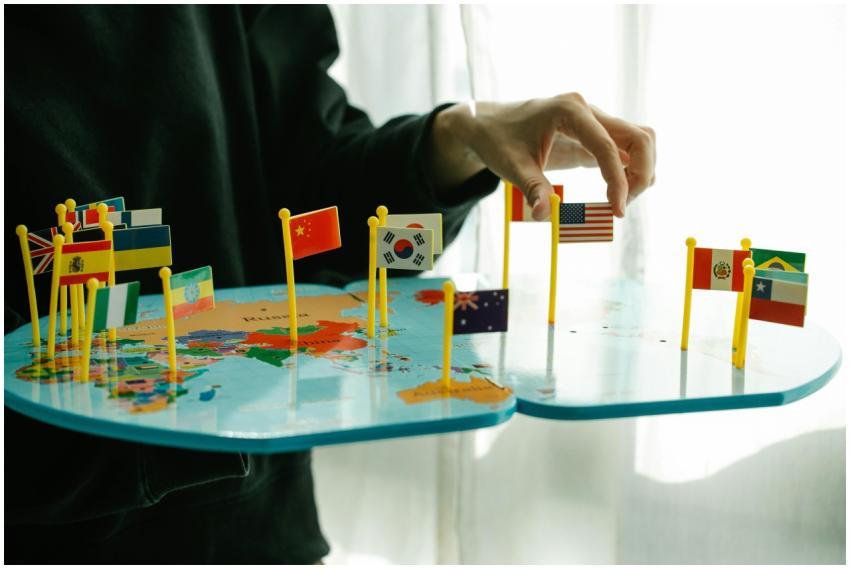 Hand arranging flags on a world map, signifying gl