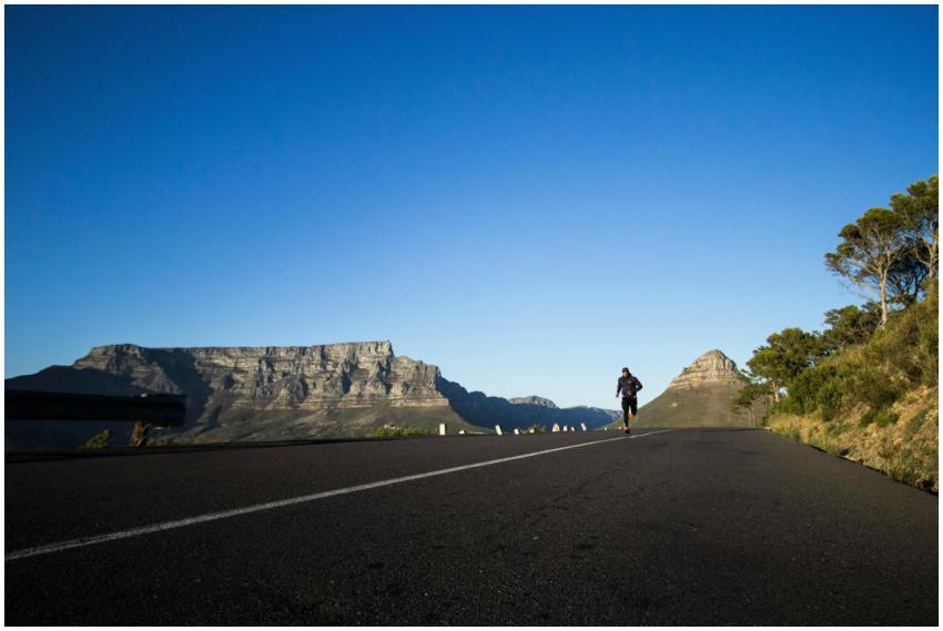 Man jogging along a scenic road with Table Mountai