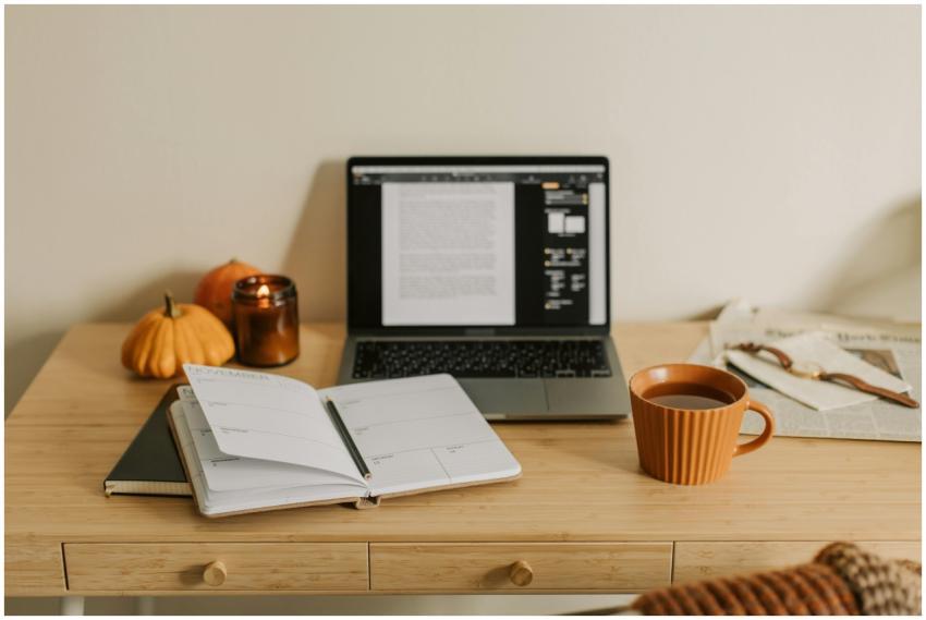 A cozy workspace featuring a laptop, coffee, noteb