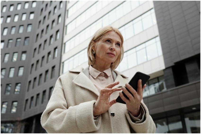 Businesswoman in a coat using a smartphone outside