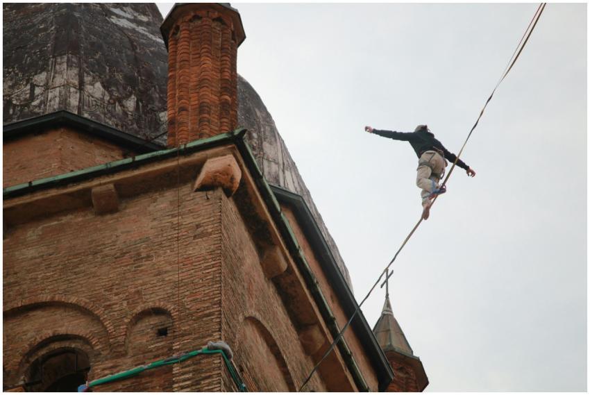 Acrobat performs on a tightrope beside a historic