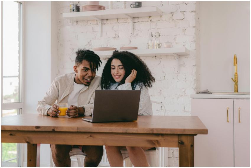 A cheerful couple sitting at a dining table, using