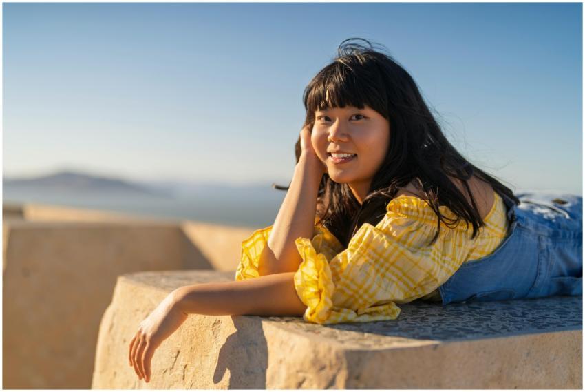 Smiling young woman in yellow shirt enjoying a sun