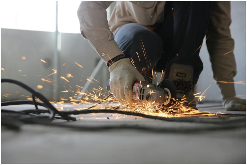 A skilled industrial worker uses a grinder creatin